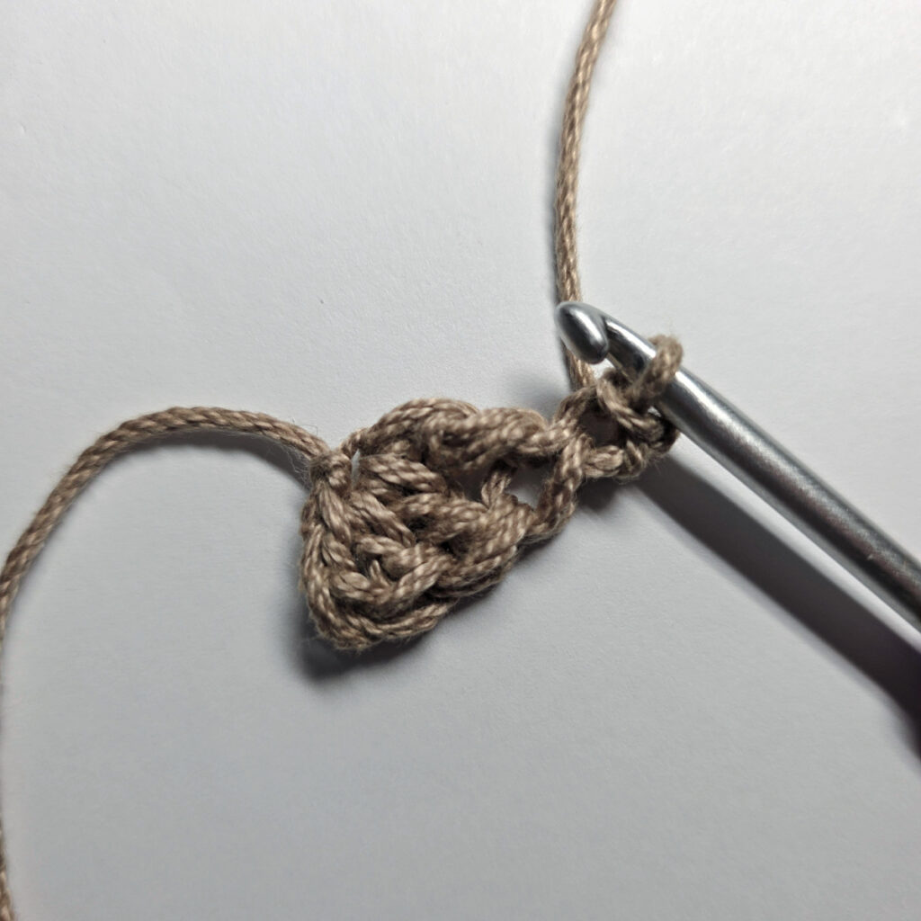 Making a crochet acorn with brown yarn.