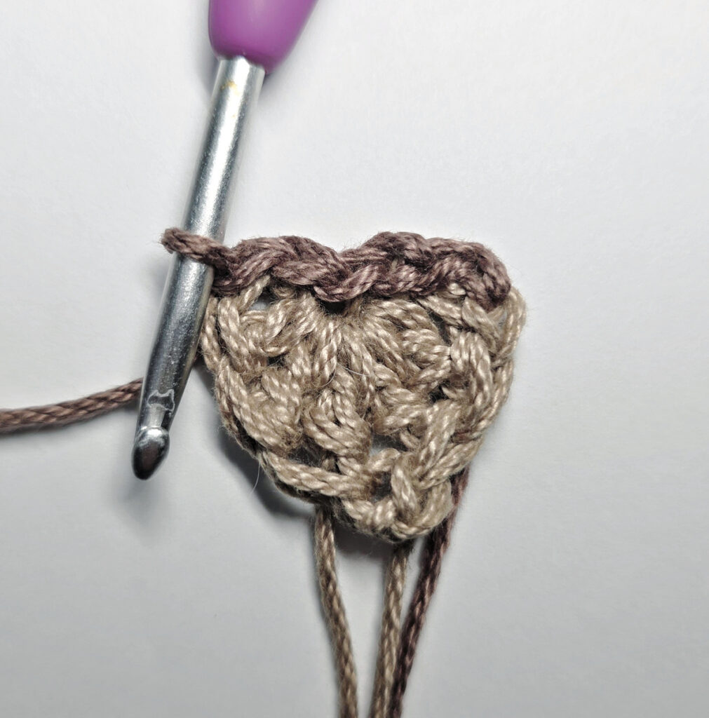 Making a crochet acorn with brown yarn.