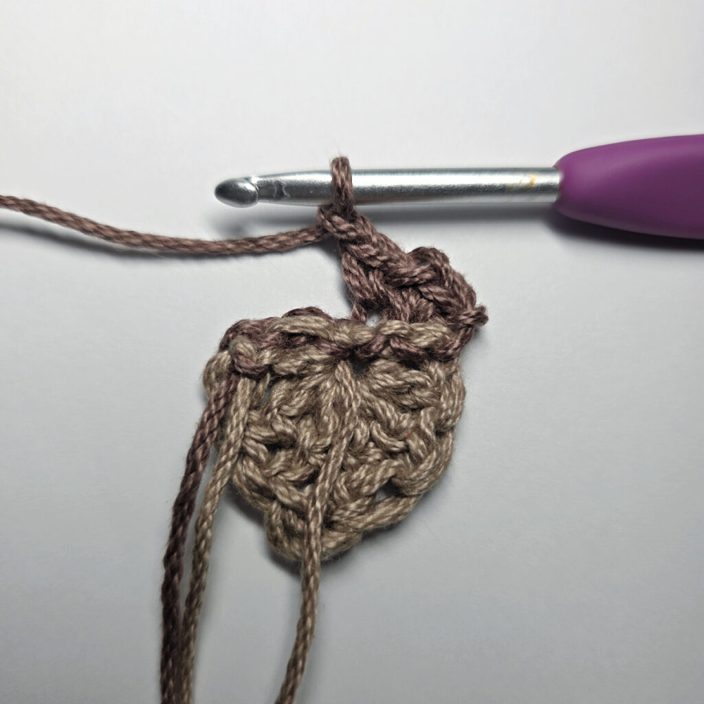 Making a crochet acorn with brown yarn.
