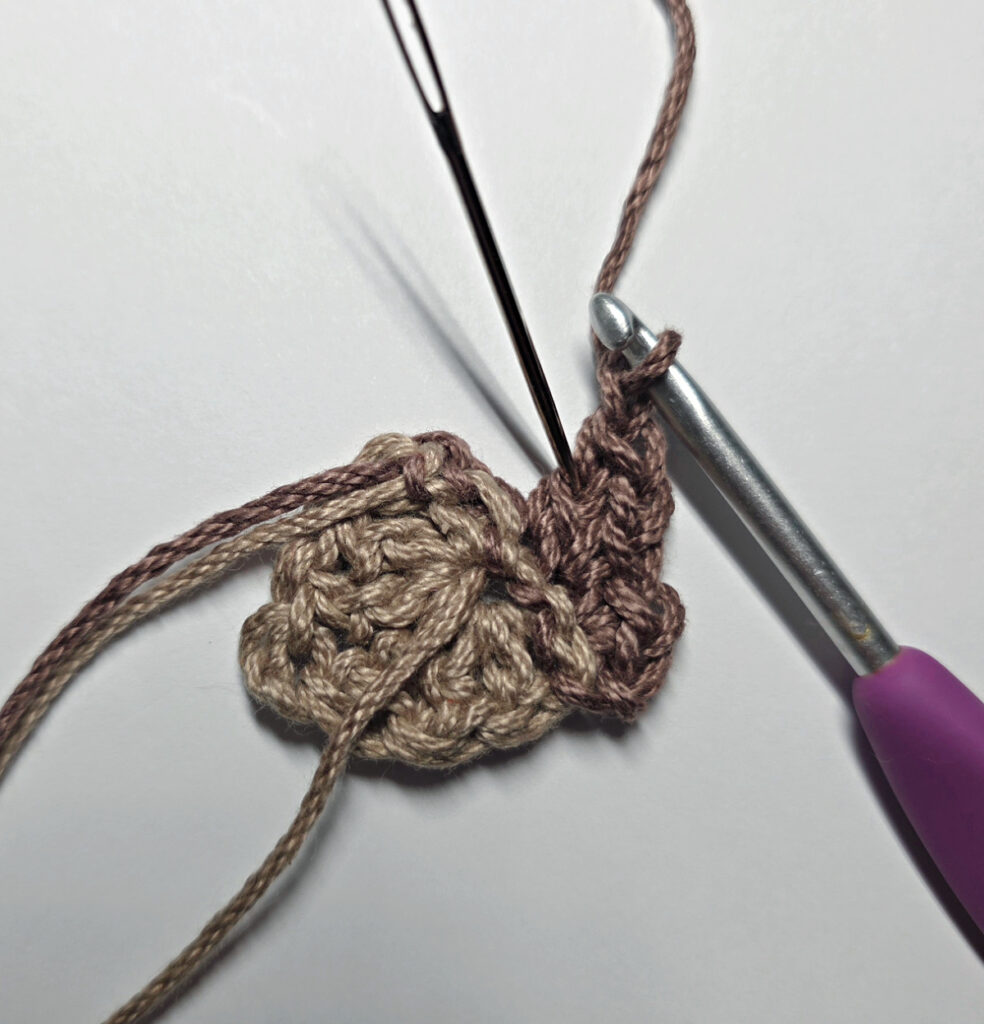 Making a crochet acorn with brown yarn.