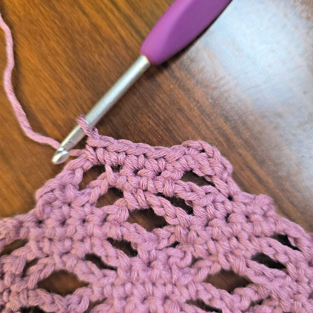 Making a crochet head scarf with a purple crochet hook.