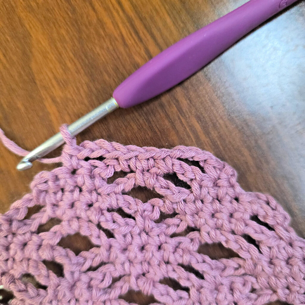Making a crochet head scarf with a purple crochet hook.