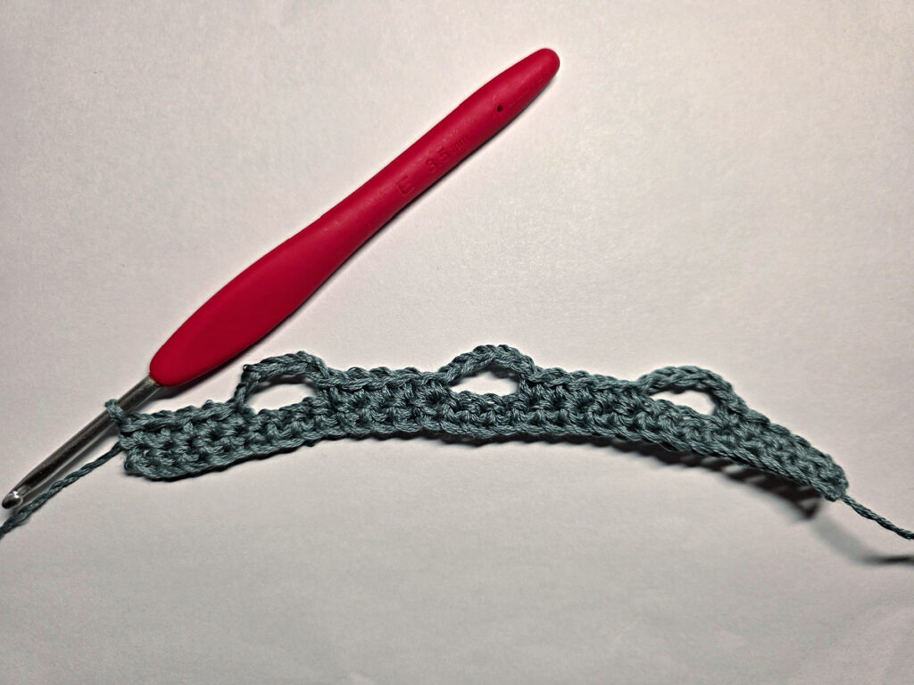 Making a crochet bandana with a red crochet hook.