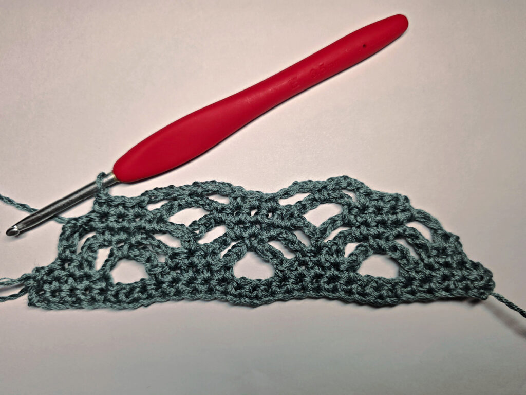 Making a crochet head scarf with a red crochet hook.