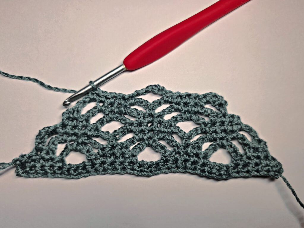 Making a crochet bandana with a red crochet hook.