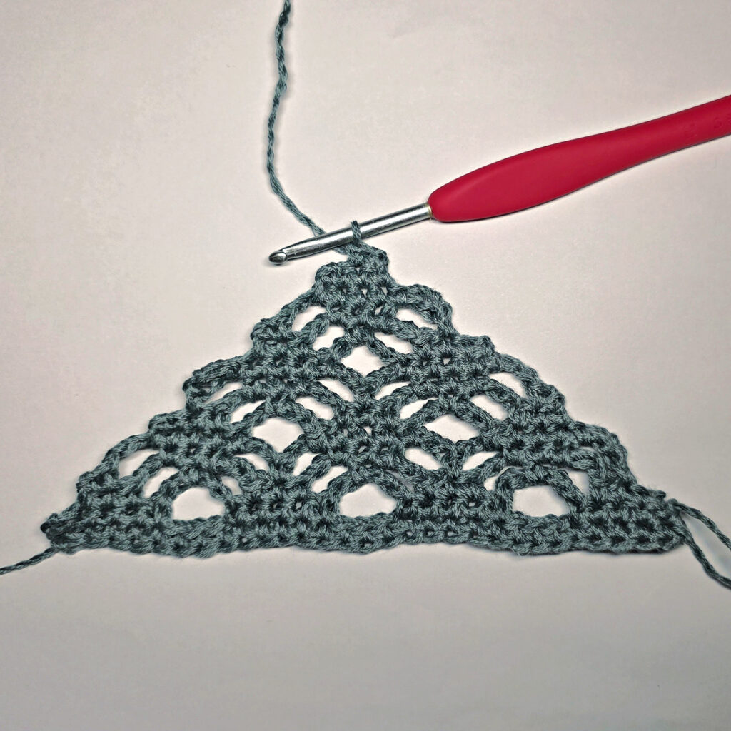Making a crochet bandana with a red crochet hook.