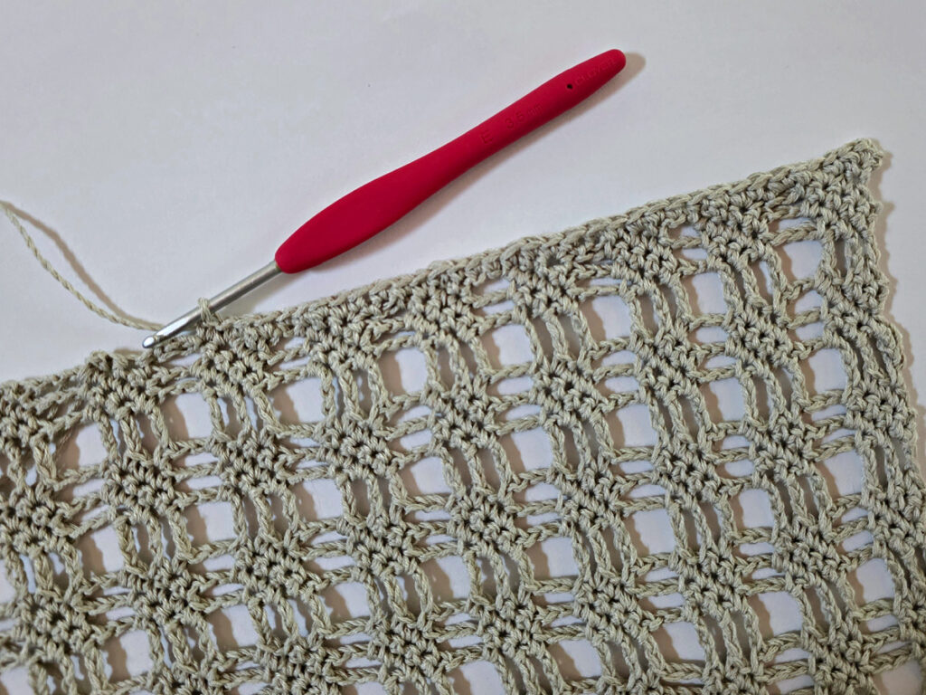 Making a crochet bandana with a red crochet hook.