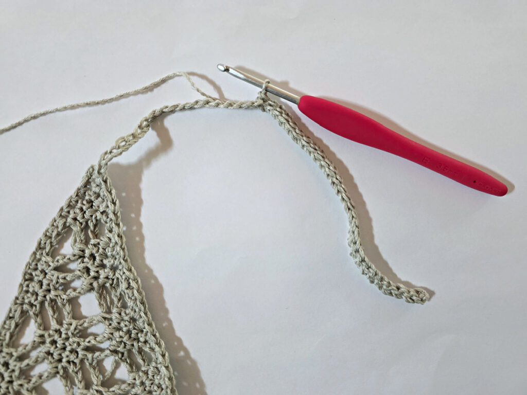 Making a crochet bandana with a red crochet hook.
