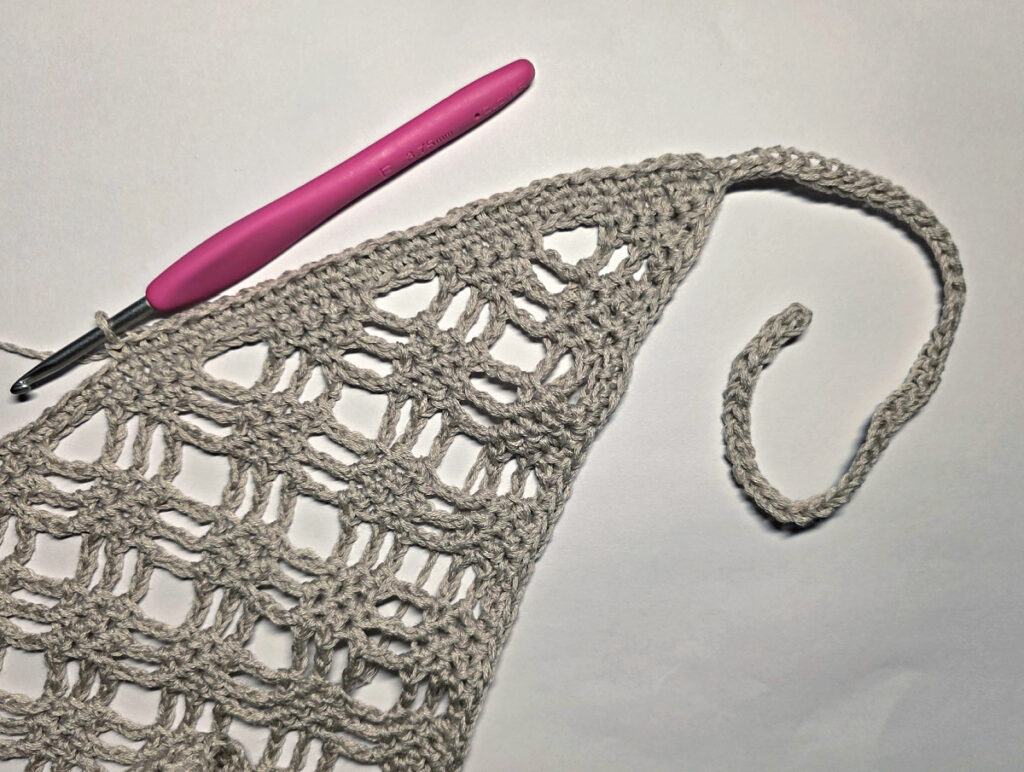 Making a crochet bandana with a pink crochet hook.