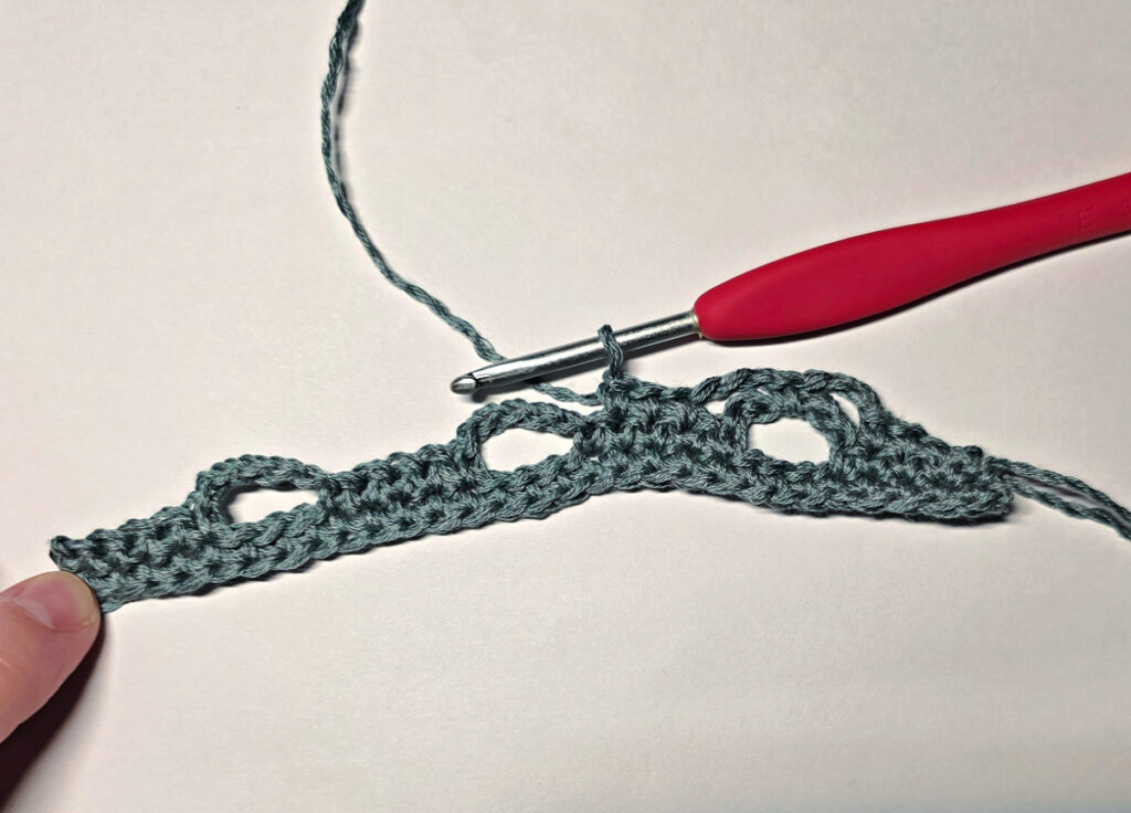 Making a crochet bandana with a red crochet hook.