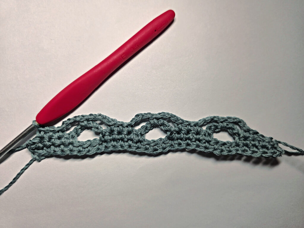 Making a crochet bandana with a red crochet hook.