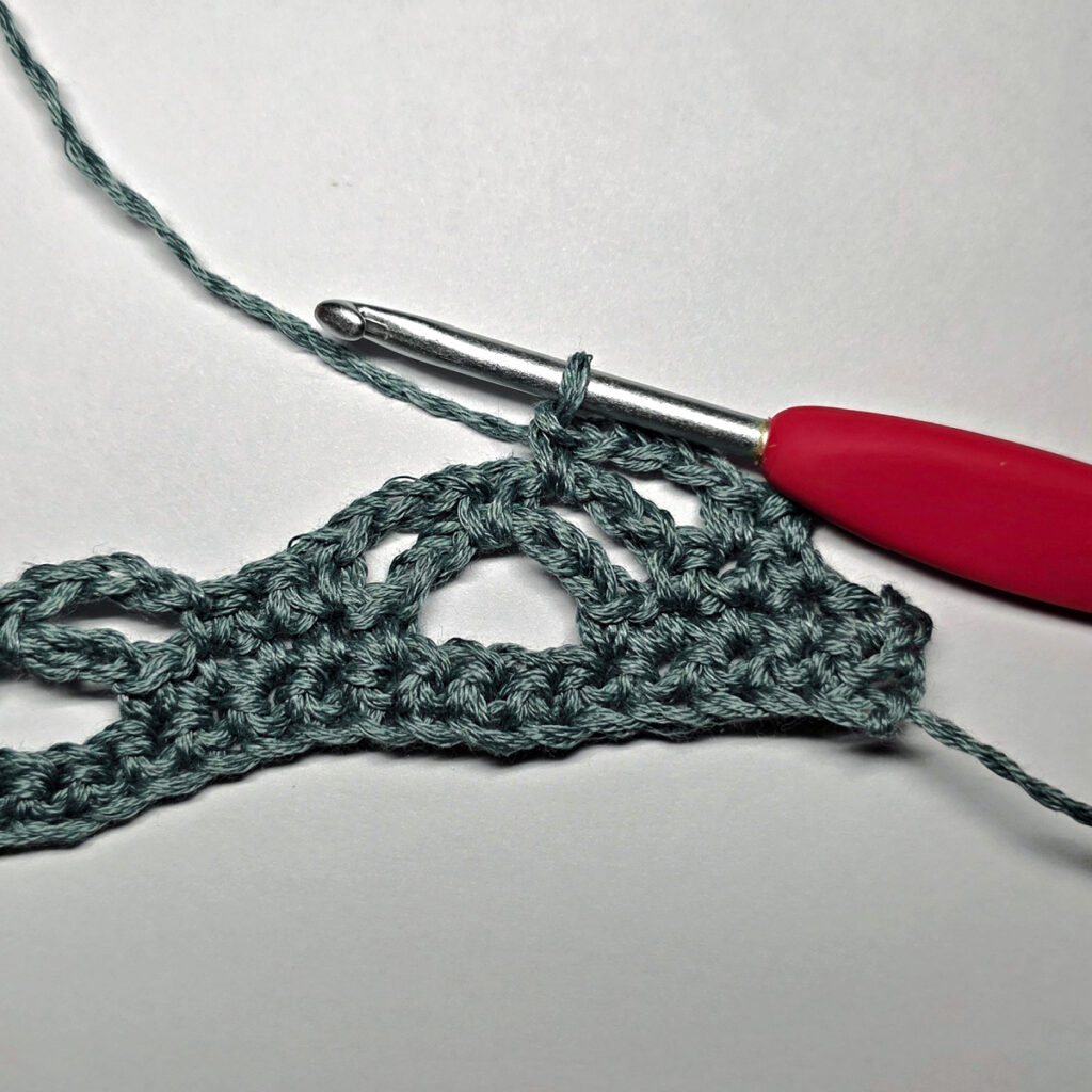 Making a crochet bandana with a red crochet hook.