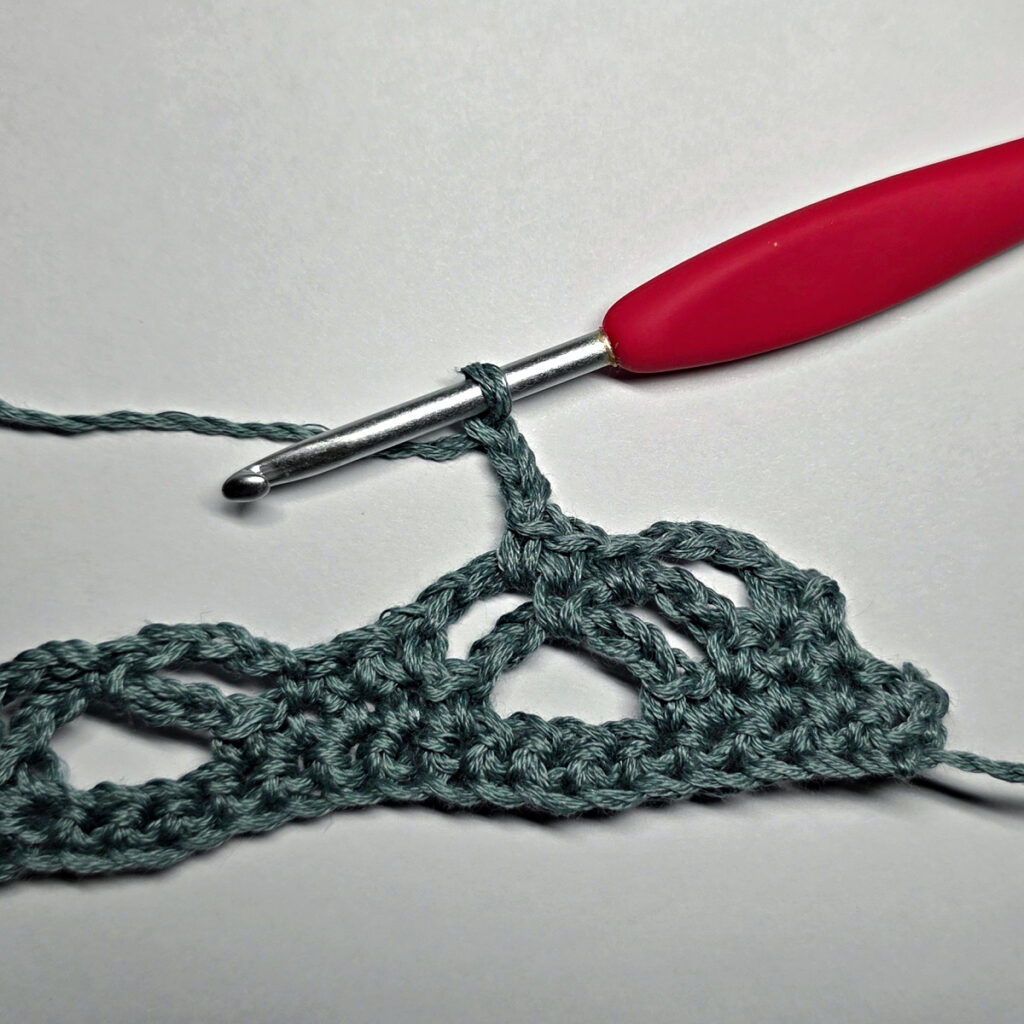 Making a crochet bandana with a red crochet hook.