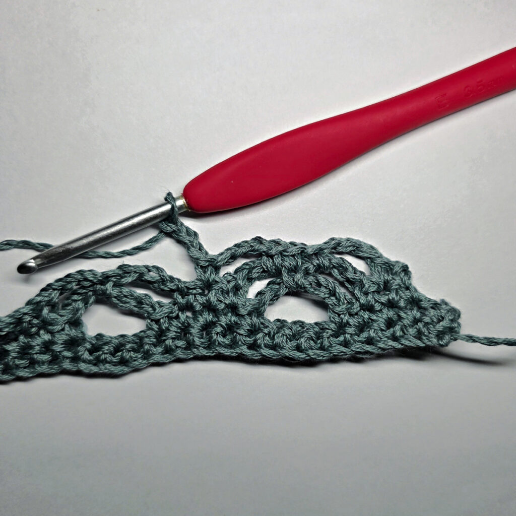 Making a crochet bandana with a red crochet hook.