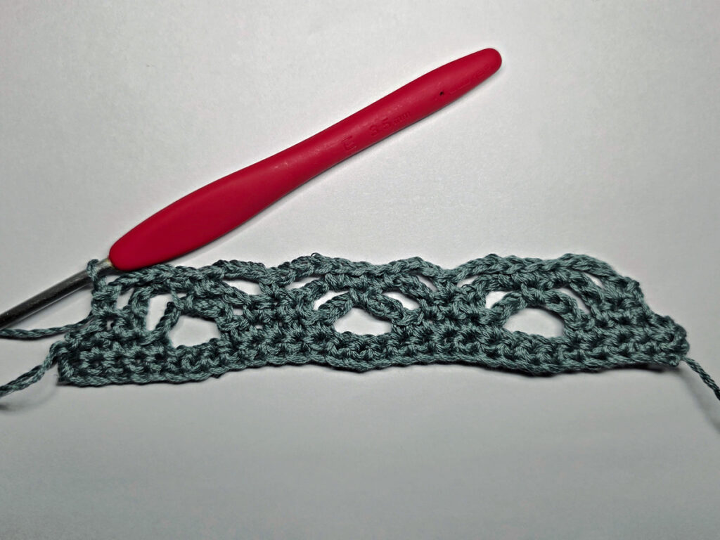 Making a crochet bandana with a red crochet hook.