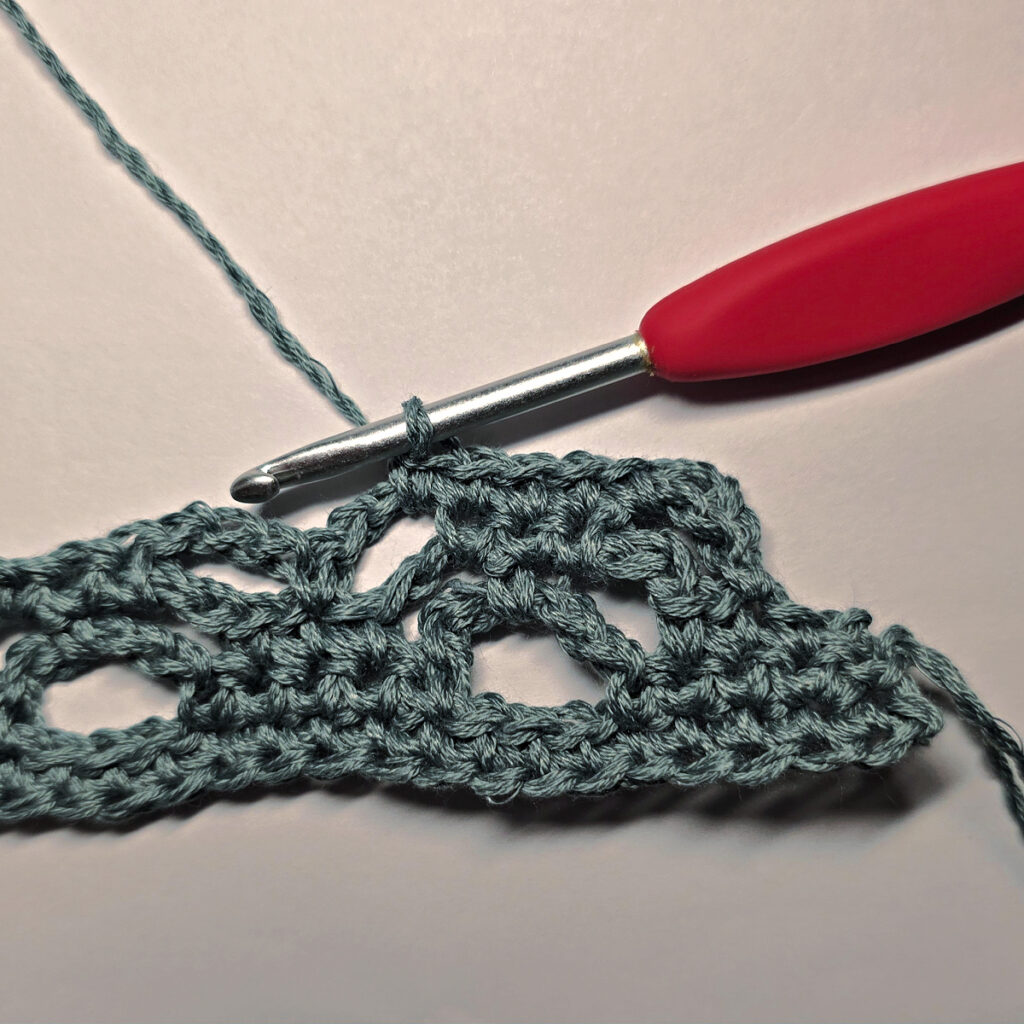 Making a crochet bandana with a red crochet hook.