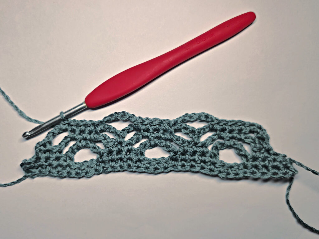 Making a crochet bandana with a red crochet hook.