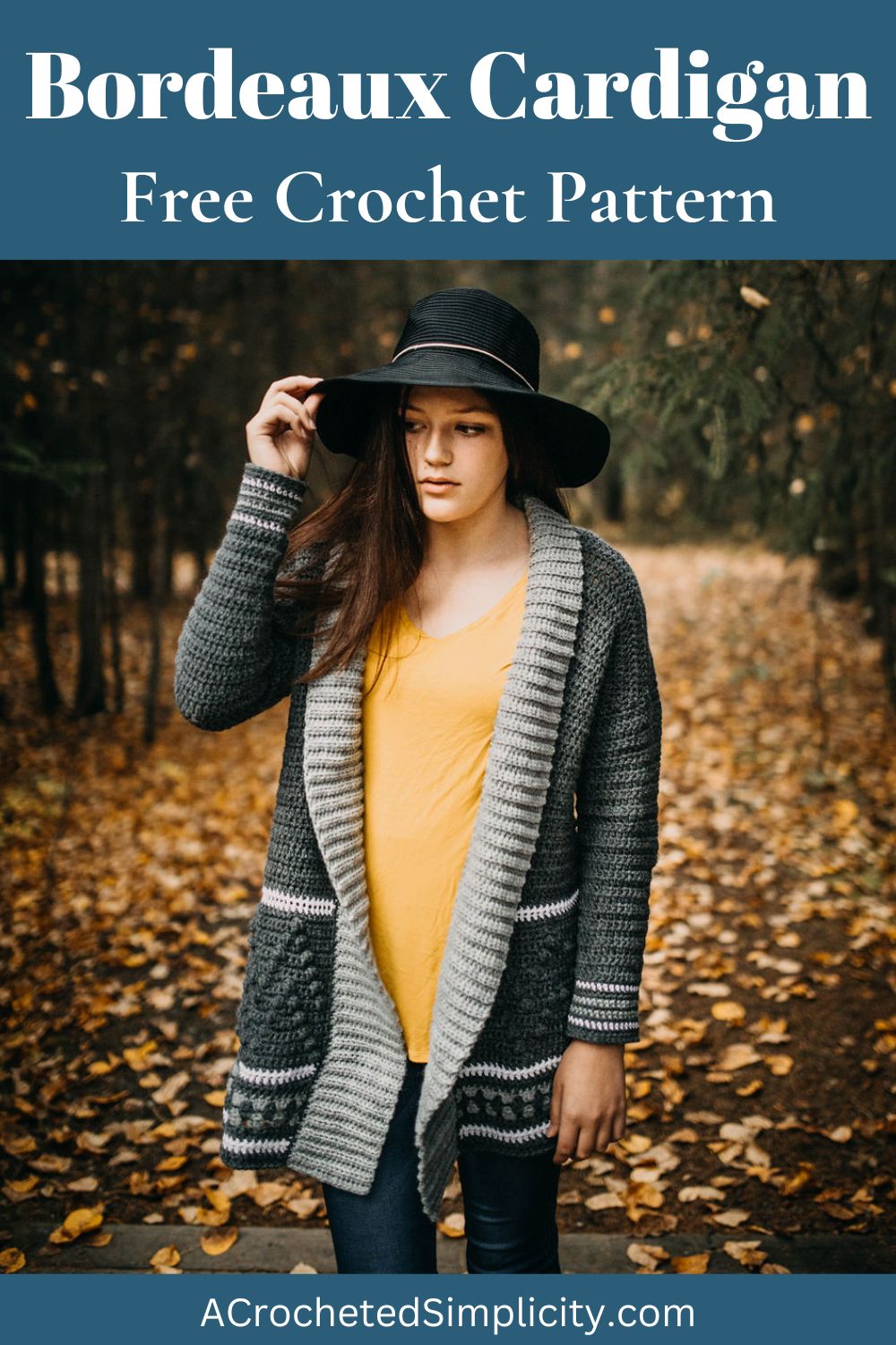 Woman wearing a grey crochet cardigan with a yellow top with her hand on the brim of a black hat.