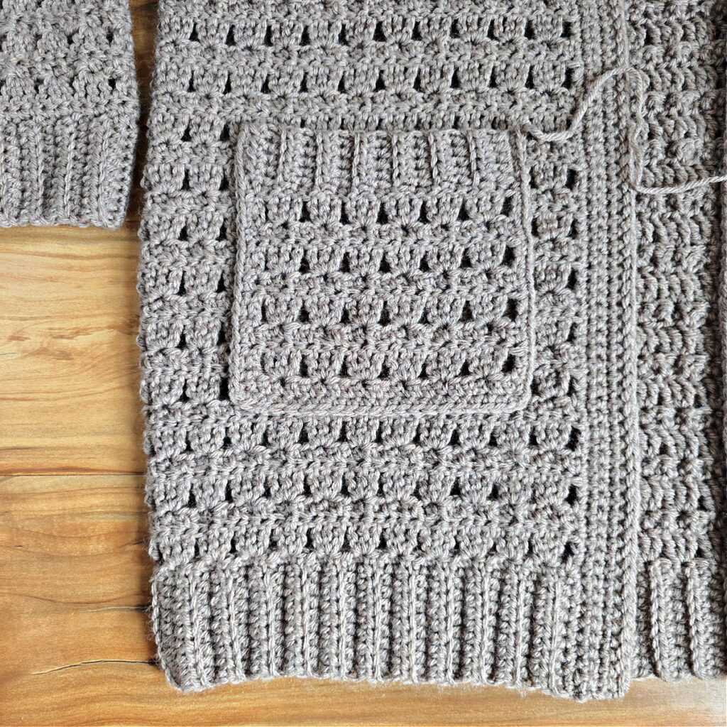 Close up photo showing where to attach a pocket to a crochet cardigan sweater.