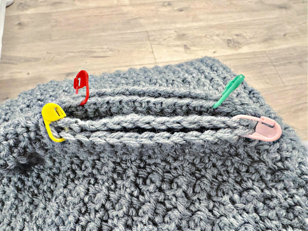 Seaming the pockets of a crochet cardigan.