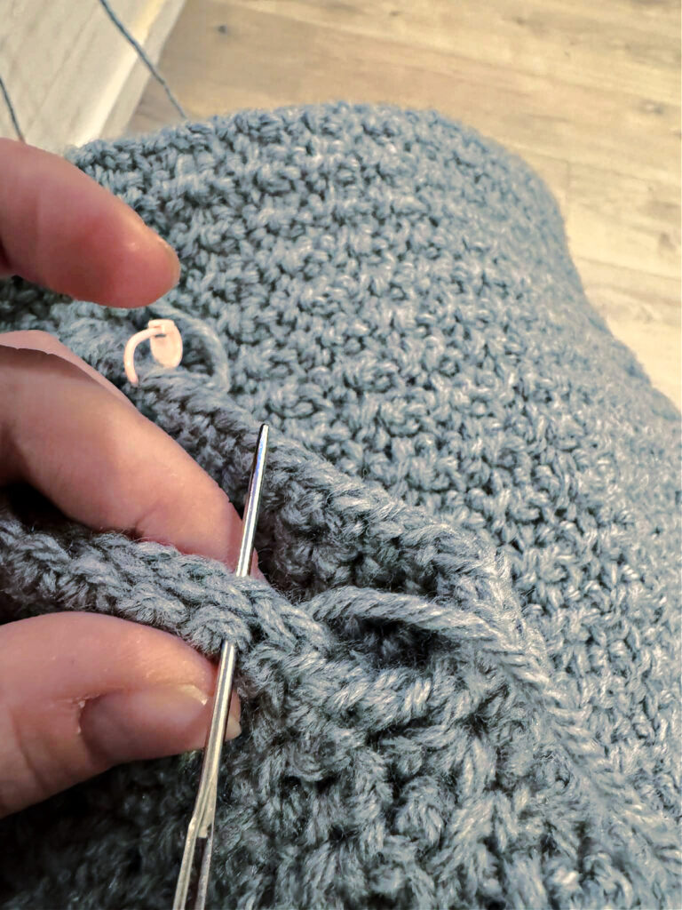 Seaming the pockets of a crochet cardigan.