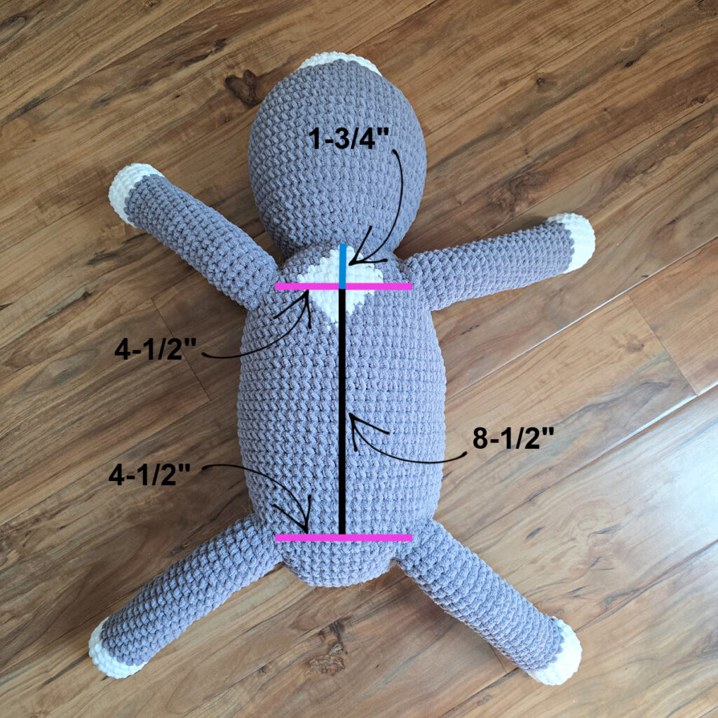 In process of assembling a crochet cat laying against a wooden floor.