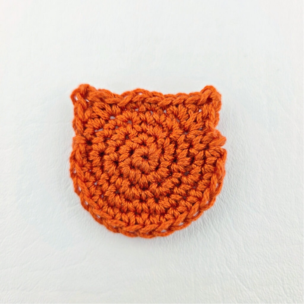 An orange crochet cat face.