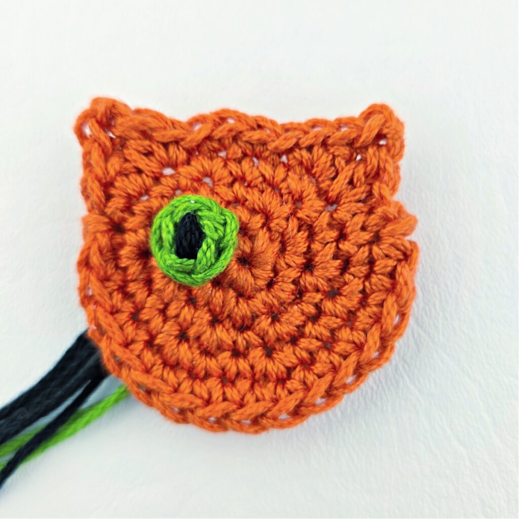 Seaming the eye of an orange crochet cat.