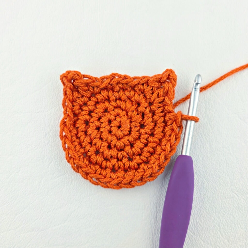 Making an orange cat crochet bookmark with a purple hook.