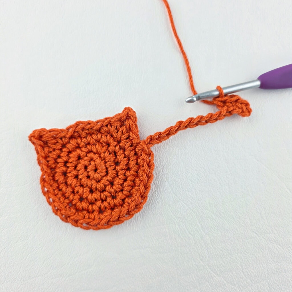 Making an orange cat crochet bookmark with a purple hook.
