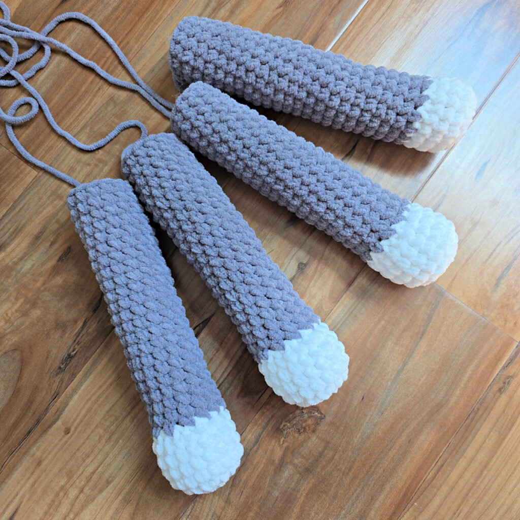 Crochet cat legs against a wooden floor.