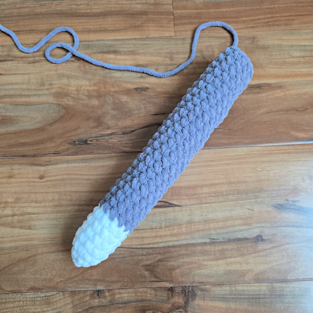 Crochet cat tail against a wooden floor.