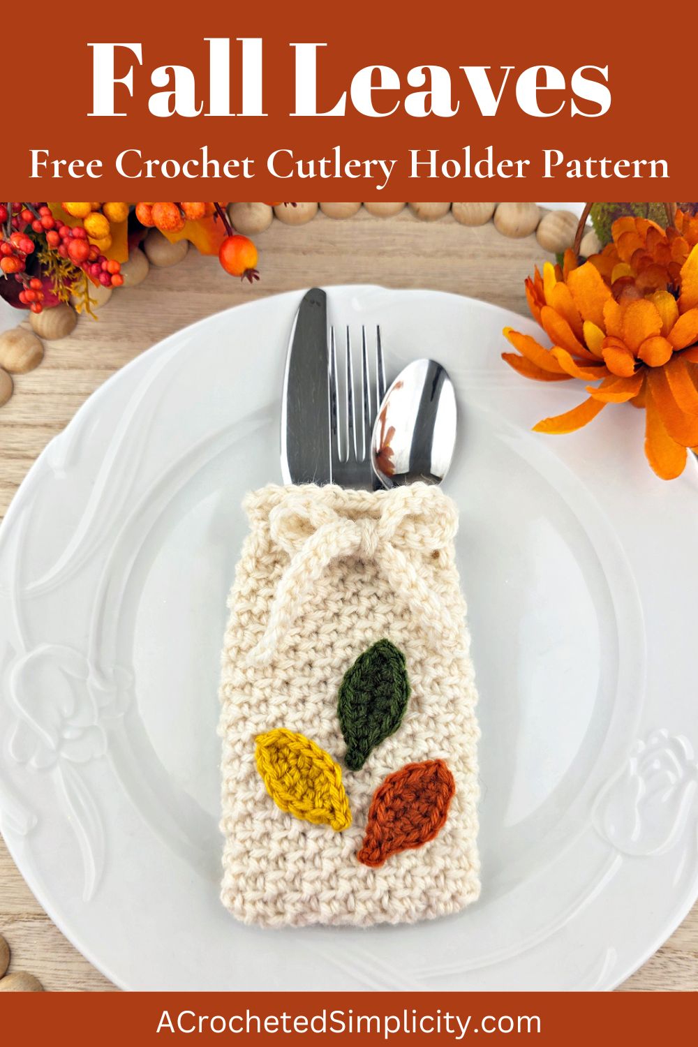 Orange, yellow, and green crochet leaves on a white cutlery holder with silverware in it on a white plate.