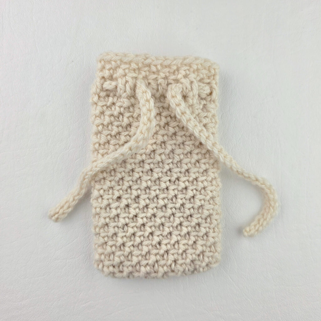 Adding a tie to a white crochet cutlery holder.