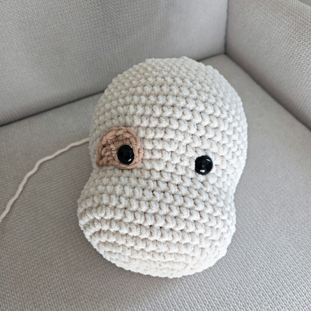 Seaming parts on the head of a plush crochet dog.