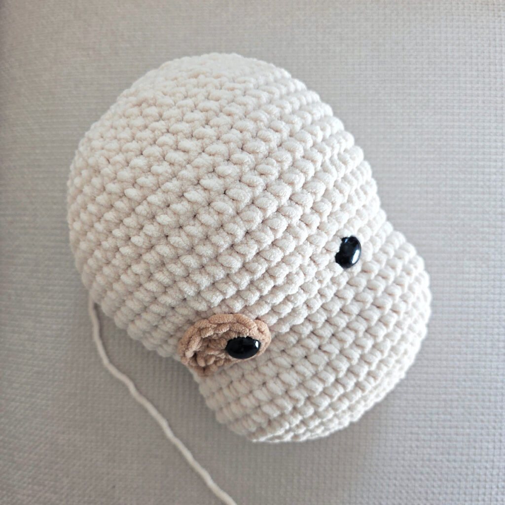 Seaming parts on the head of a plush crochet dog.