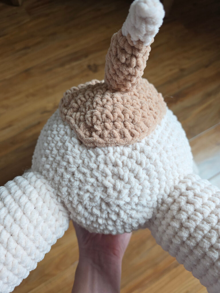The back of a crochet dog to show where to attach the heart patch with his tail.