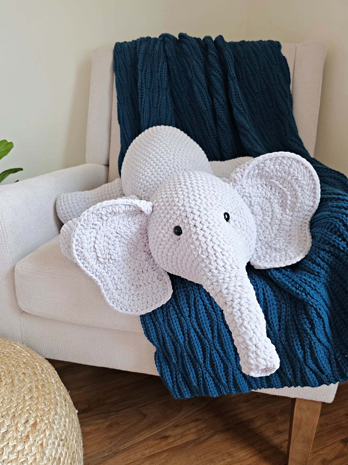 A large gray amigurumi elephant on a blue blanket spread on a sofa.