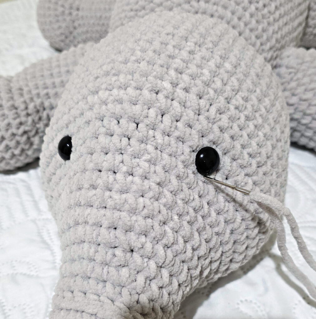 A gray crochet elephant head in progress.