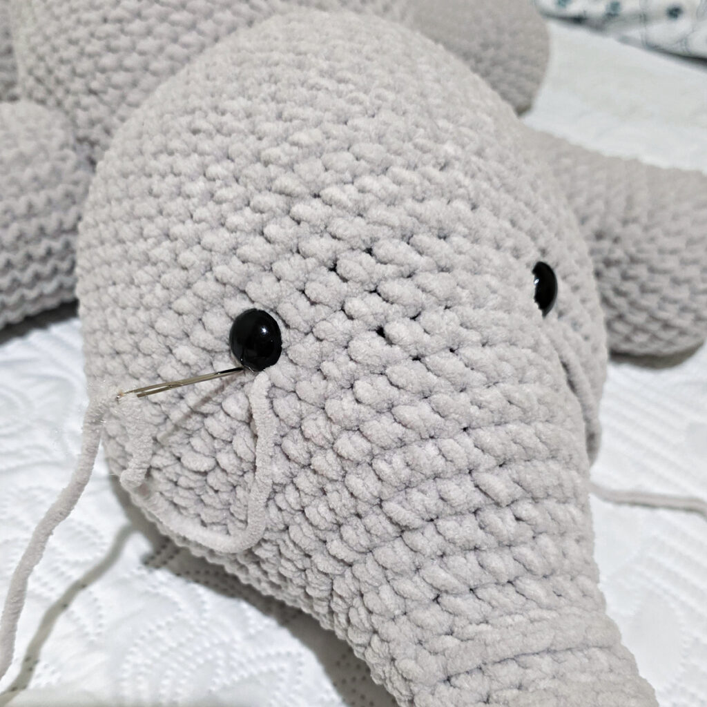 A gray crochet elephant head in progress.