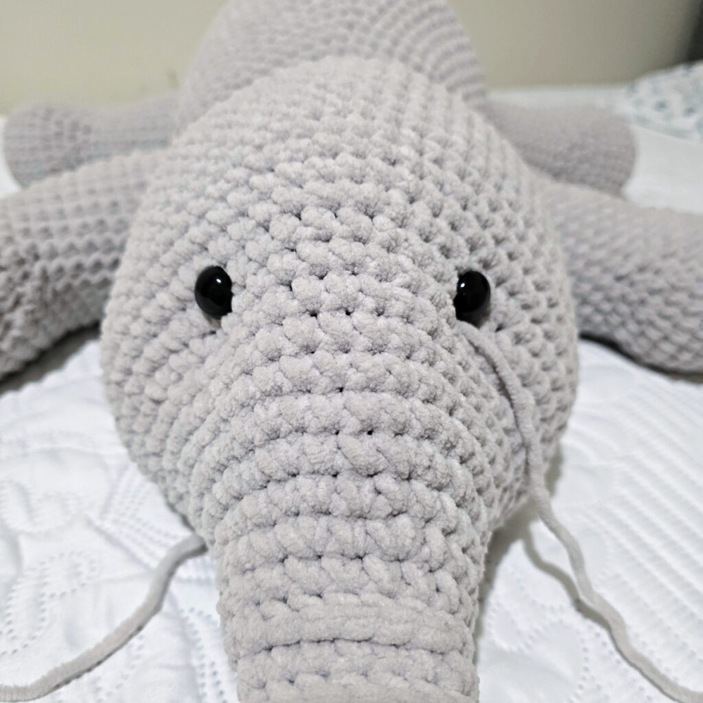 A gray crochet elephant head in progress.