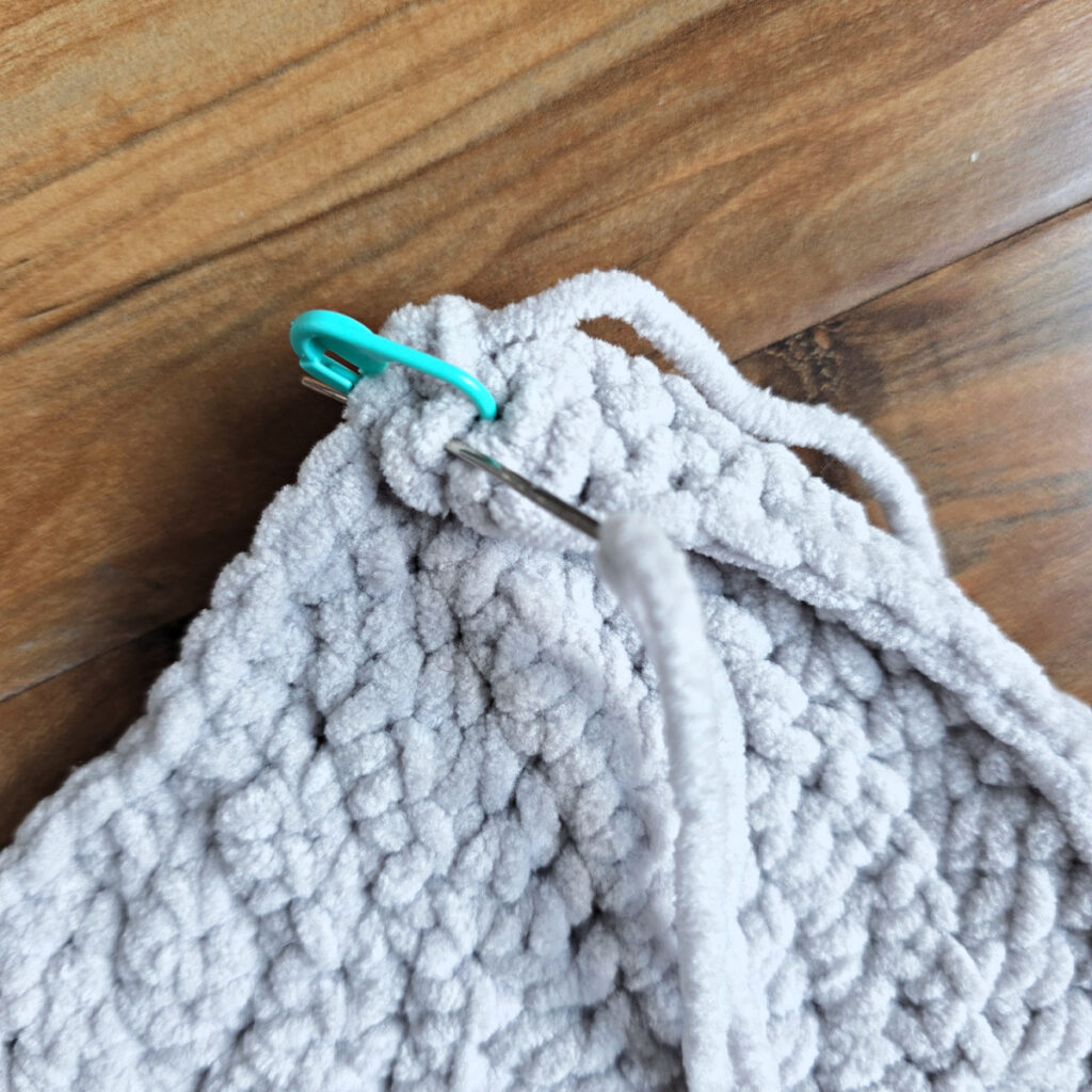 A gray crochet elephant ear in progress on a wooden floor.