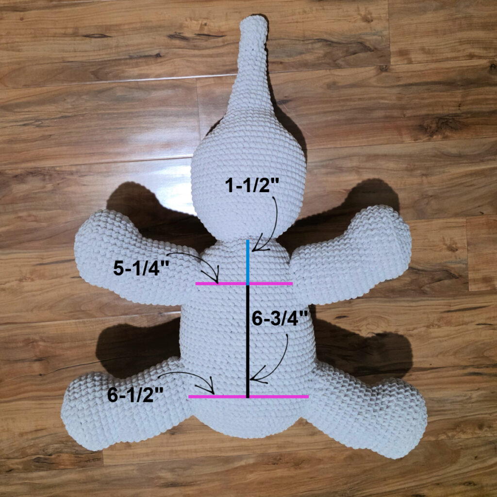 A gray crochet elephant in progress on a wooden floor.
