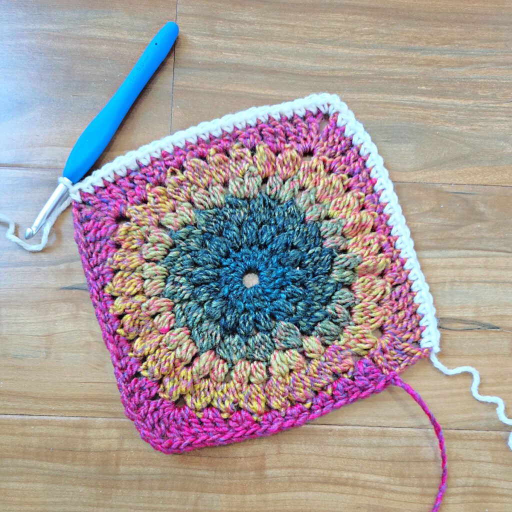 Border being added to a colorful crochet floral square.
