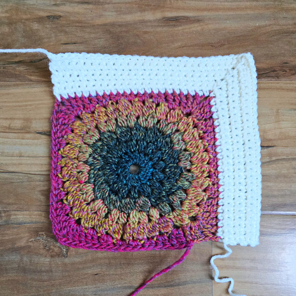 Border being added to a colorful crochet floral square.
