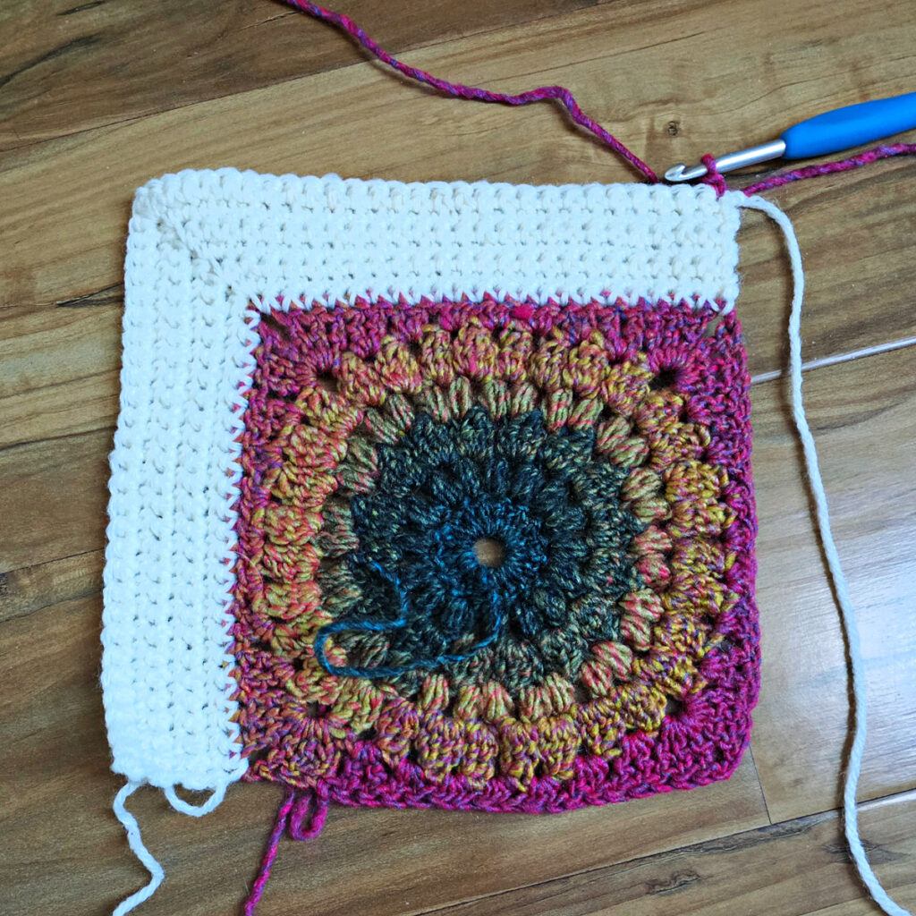 Border being added to a colorful crochet floral square.