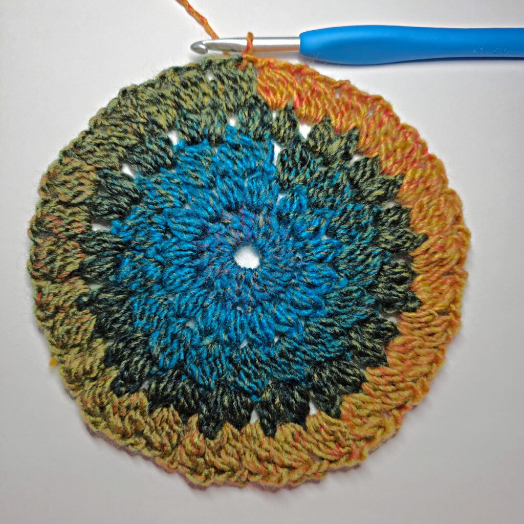 How to work a crochet floral square with a blue crochet hook.