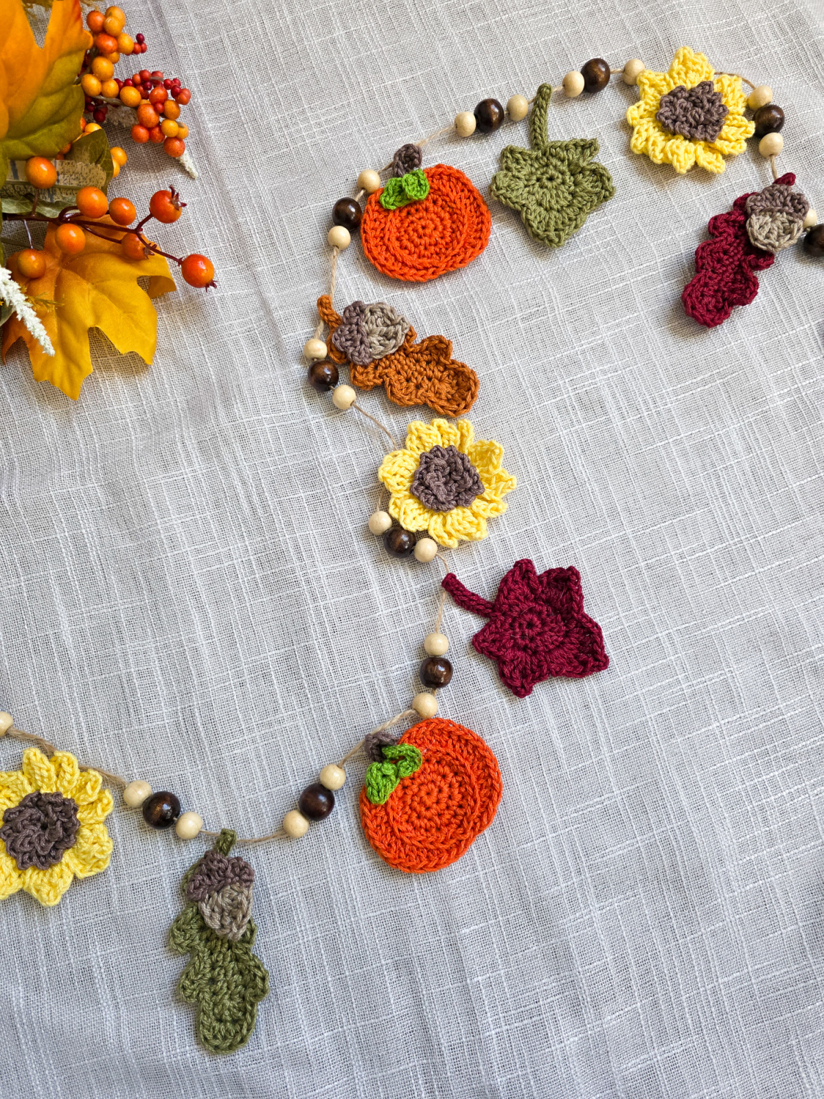 A colorful autumn harvest crochet garland with sunflowers, pumpkins, and leaves.