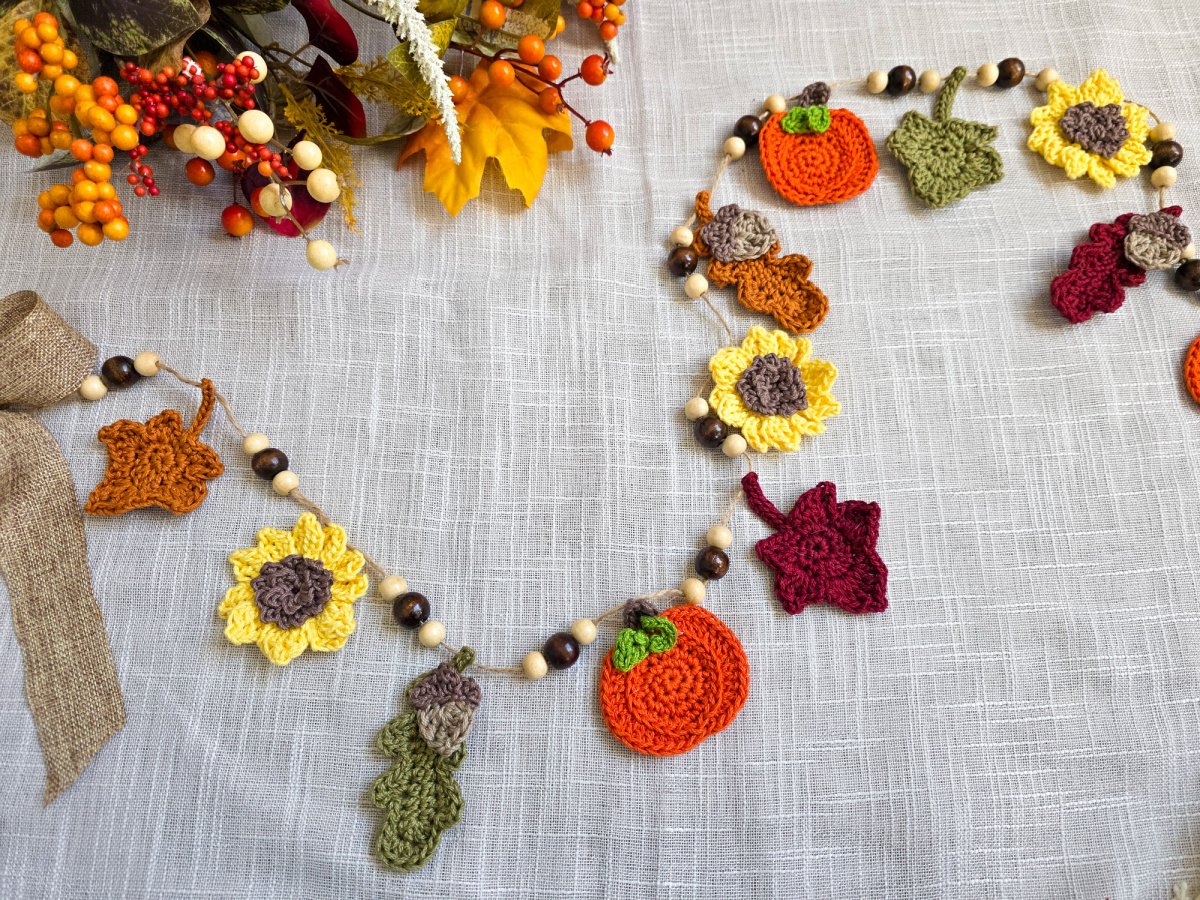 A colorful autumn harvest crochet garland with sunflowers, pumpkins, and leaves.