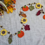 A colorful autumn harvest crochet garland with sunflowers, pumpkins, and leaves.